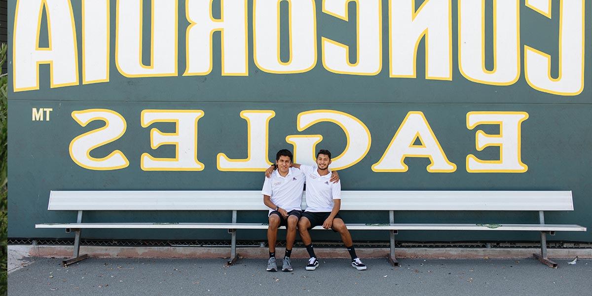 The Aguirre brothers sitting in front of the Concordia Eagles sign